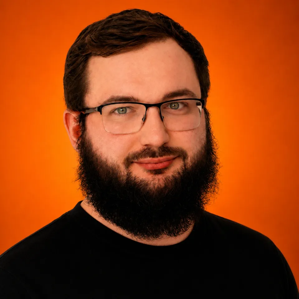 Kyrylo Riabykh in glasses and a black T-shirt, smiling, against an orange background